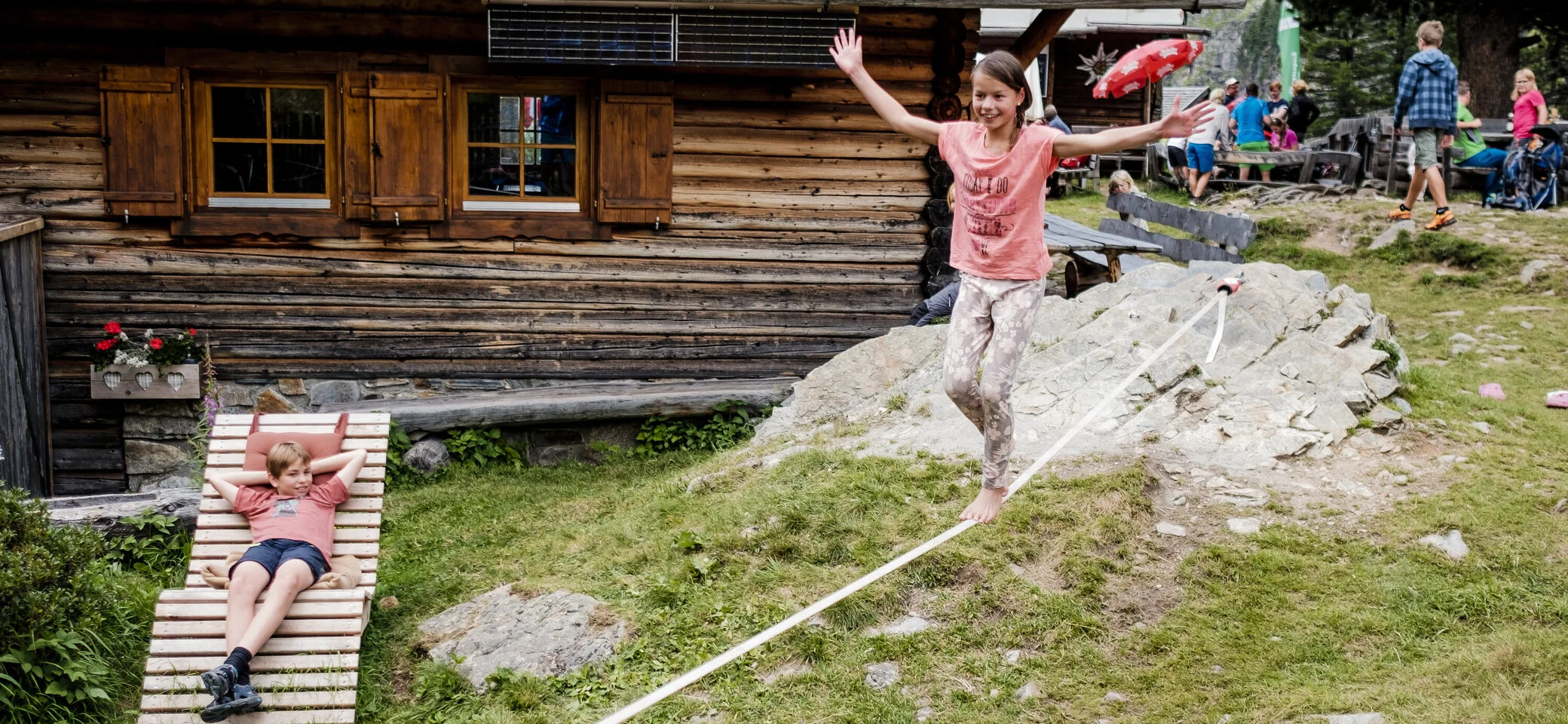 Mit Kindern in den Bergen | © DAV/Hans Herbig Zwei Kinder balancieren auf einem Seil, das vor einer Berghütte gespannt ist | © DAV/Hans Herbig